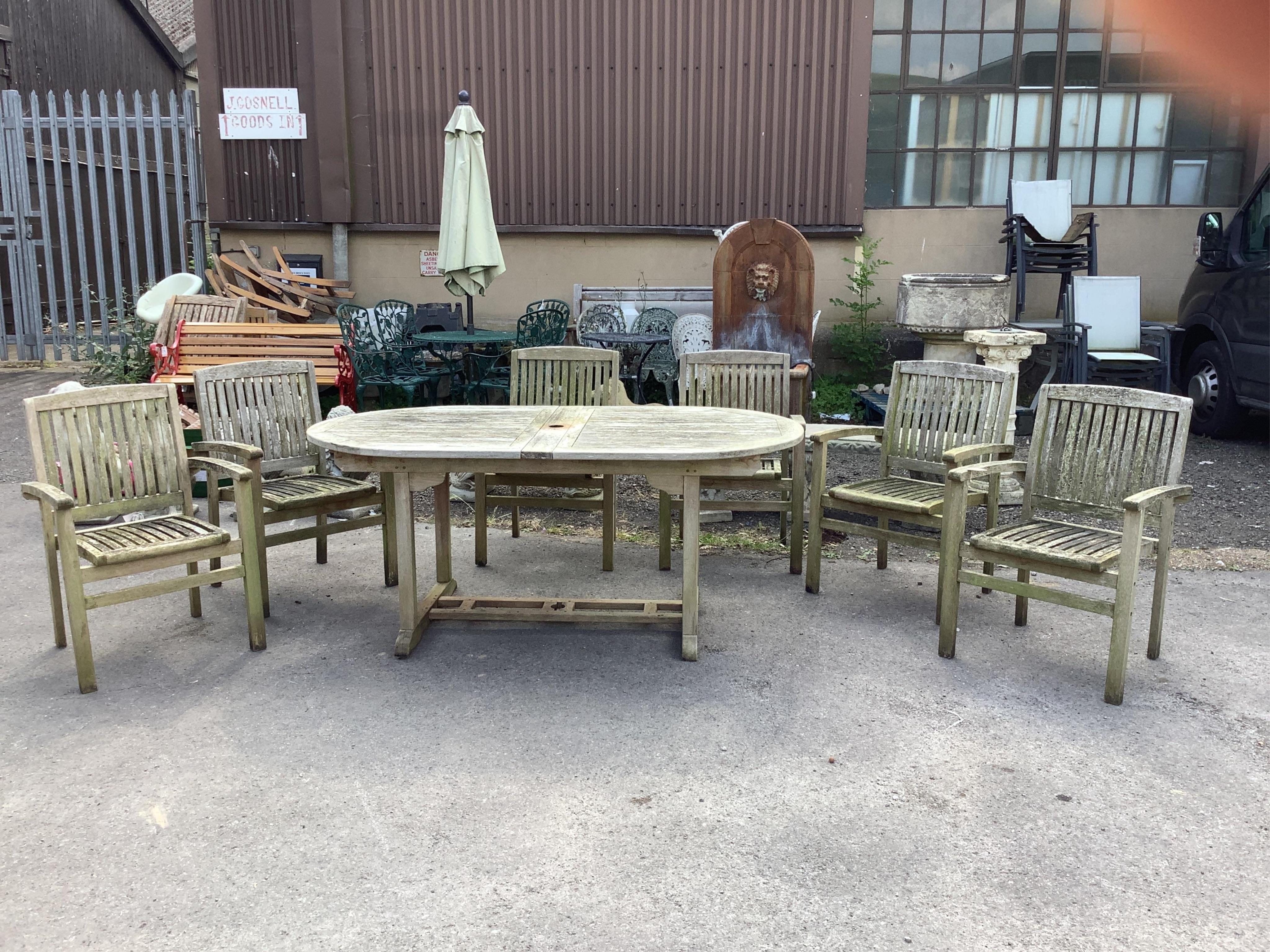 A “Kyoto” weathered teak extending garden table, width 240cm extended, depth 100cm, height 75cm, together with six stacking elbow chairs. Condition - fair